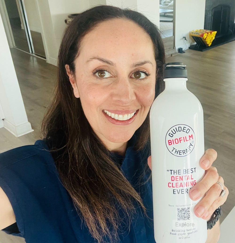 Dr. Safapour with a Guided Biofilm Therapy bottle — the best dental cleaning ever