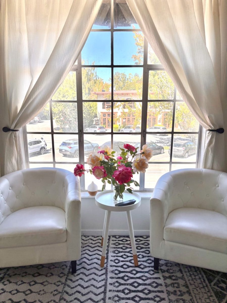 Signature Smiles waiting room — two white armchairs by the window with fresh roses