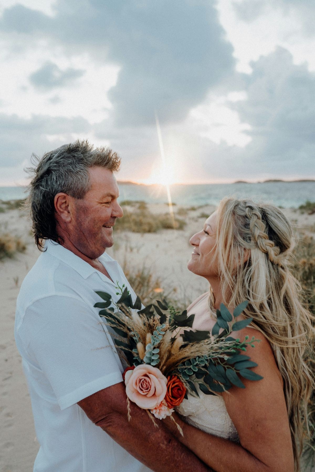 Couple smiling at each other on the beach at sunset