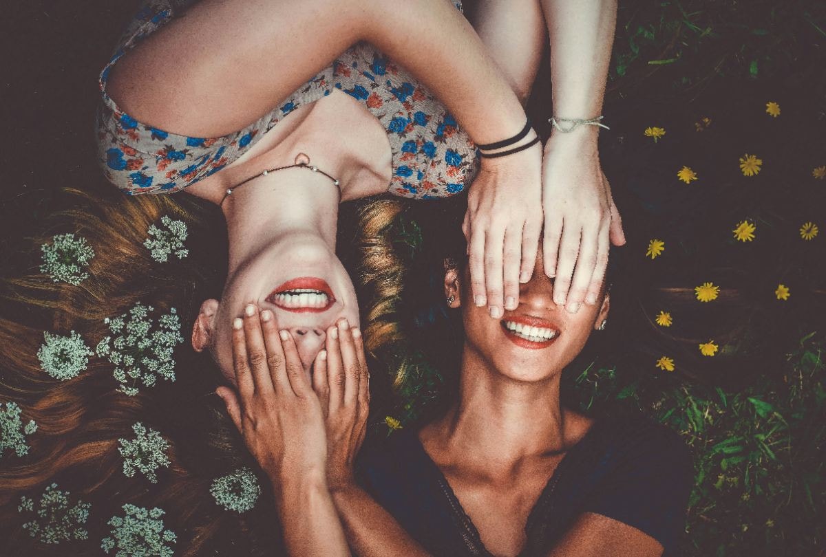 Two friends lying in a field of flowers laughing